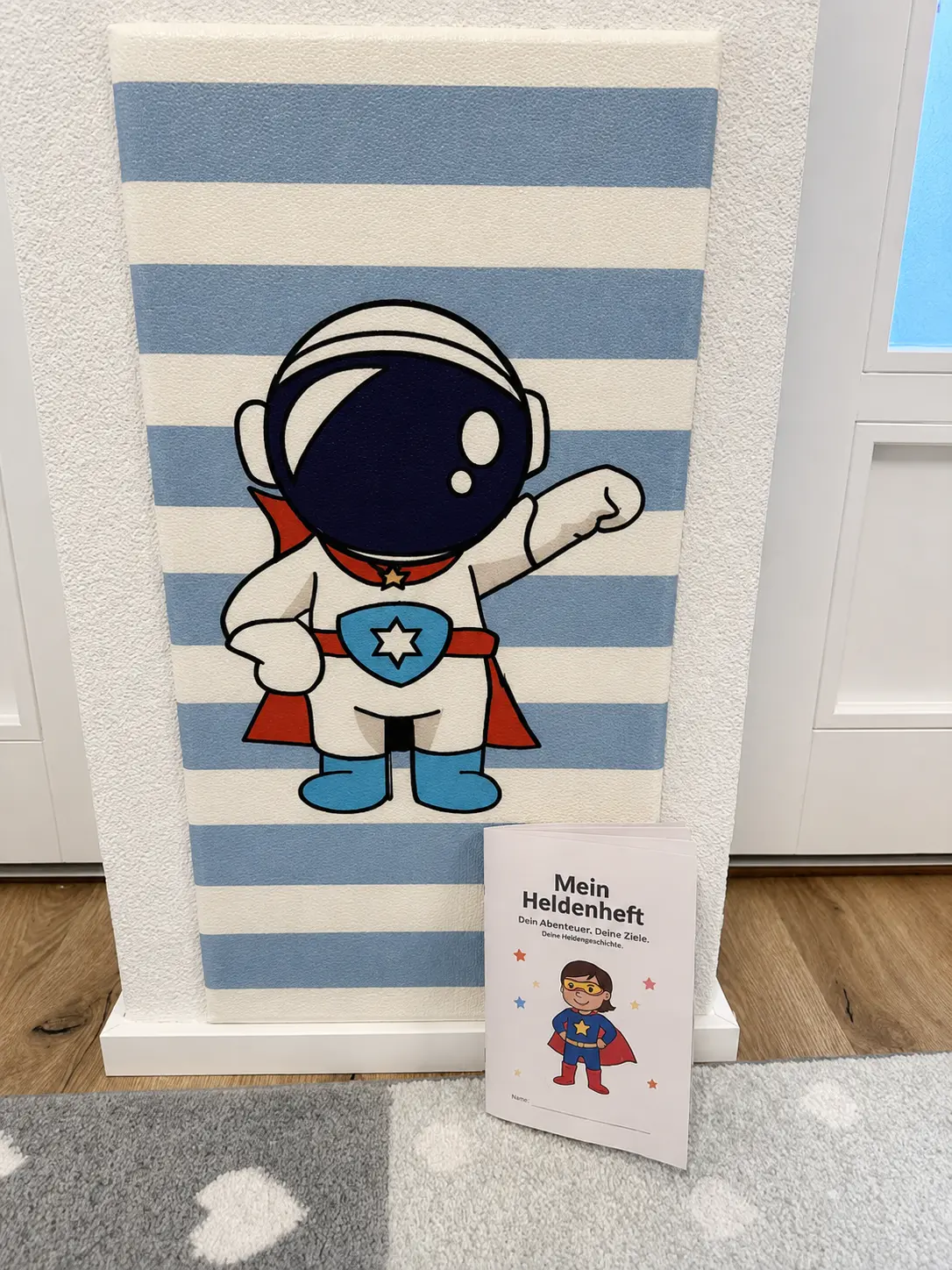 Astronauten-Superhelden-Wandbild mit FOKUS⁺ Heldenheft im Praxisraum Horgen